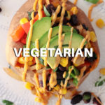 stuffed sweet potato with black beans corn tomato and avocado slices with southwest sauce drizzled on top