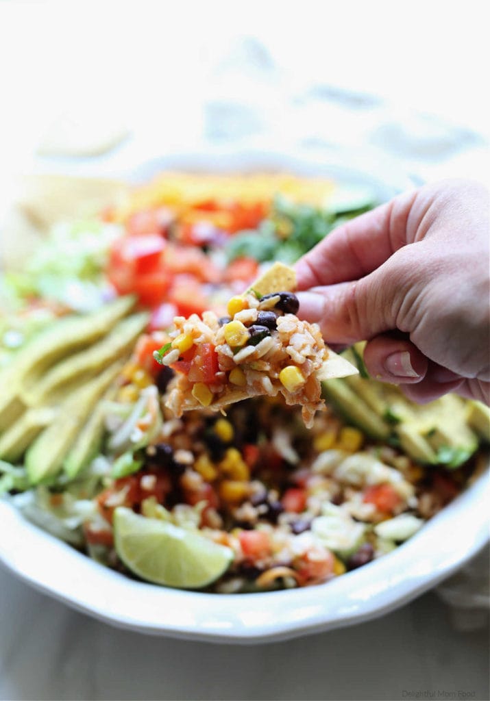 hand scooping taco salad onto a tortilla chip
