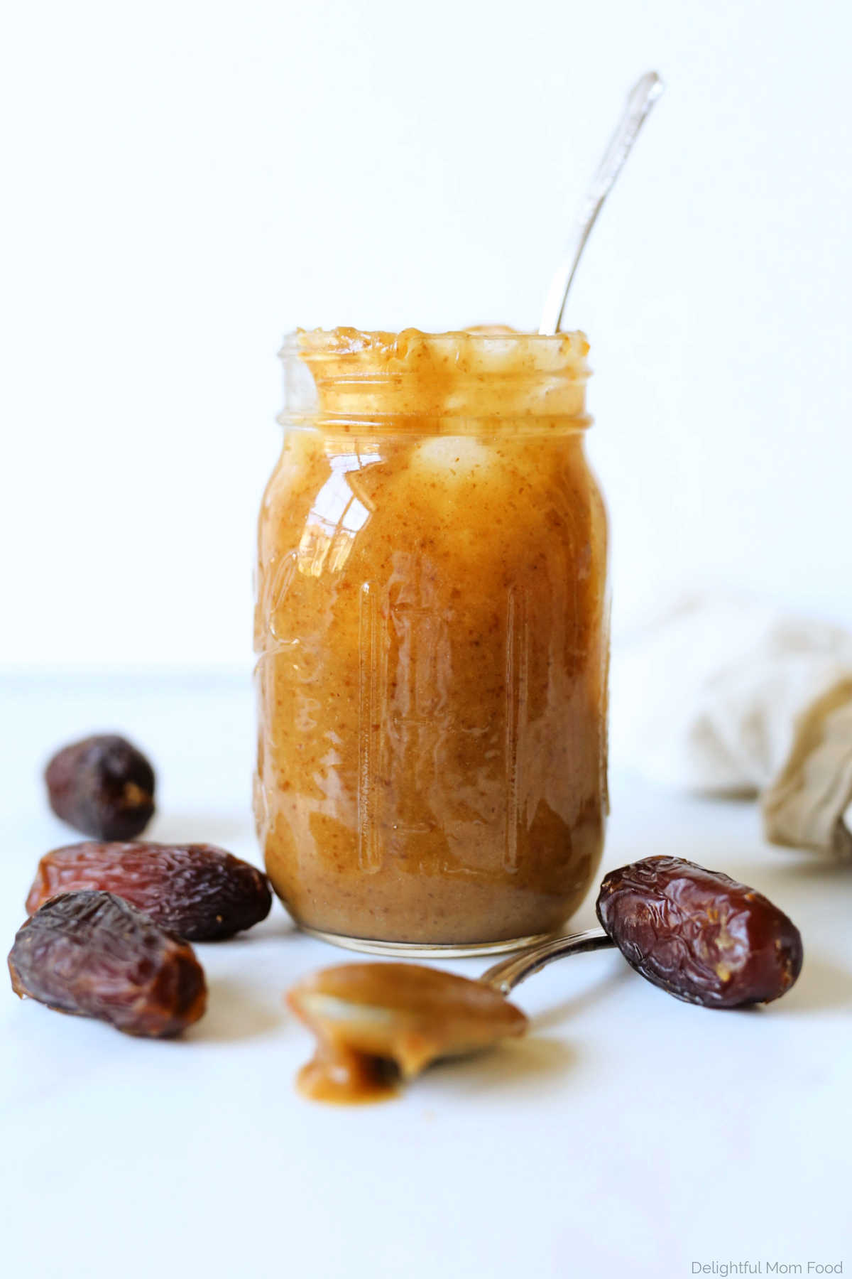 vegan date caramel sauce in a mason jar on a counter with a spoon and date fruit