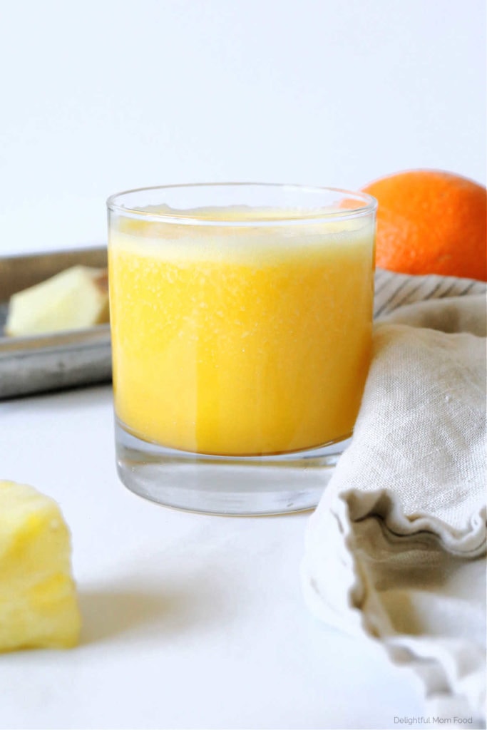 glass of fresh orange pineapple juice by a dish towel