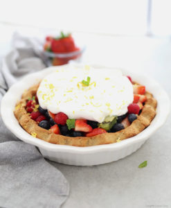 paleo pie filled with fresh fruit and whipped cream topping