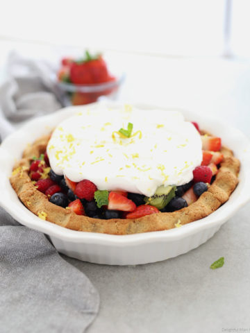 Paleo pie filled with fresh fruit and whipped cream topping.