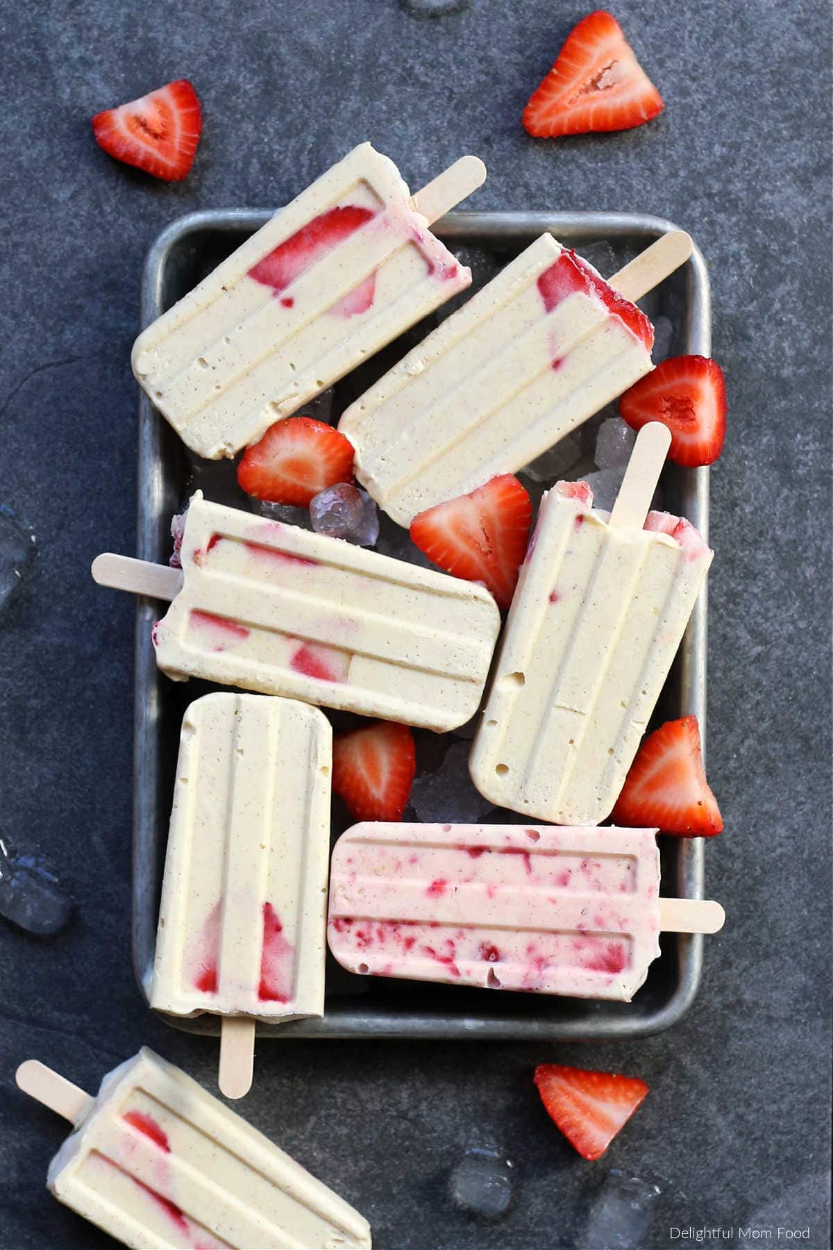 cheesecake popsicles on a tray with strawberries and ice