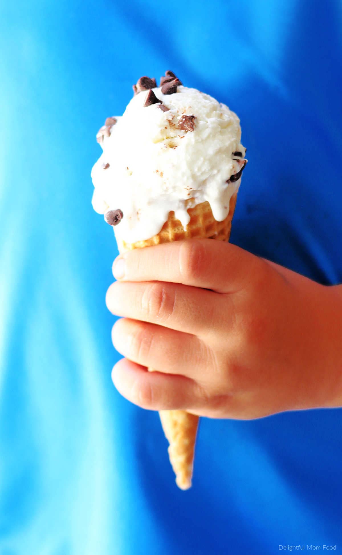 boys hand holding a greek yogurt mint chocolate chip ice cream cone