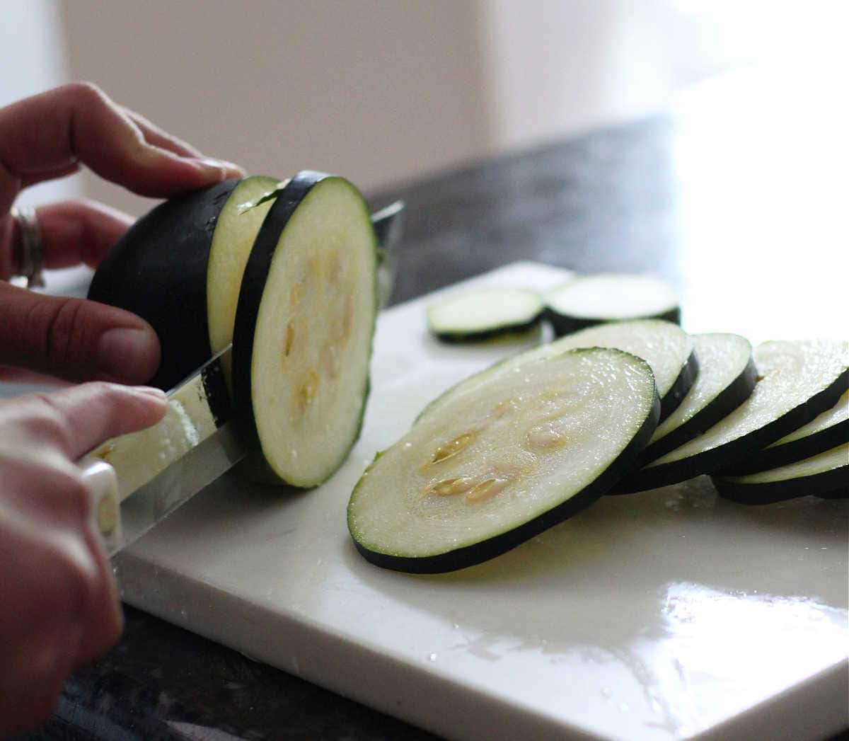 slicing zucchini into thin coin slices.