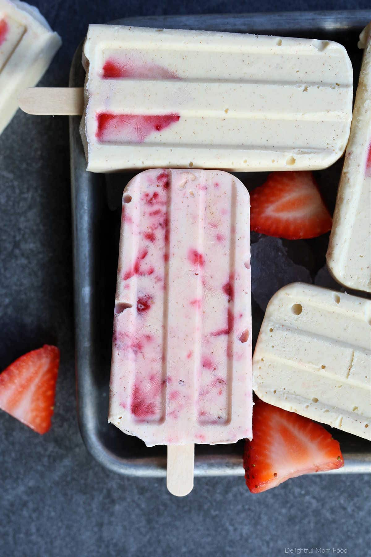 strawberry cheesecake popsicles on a tray with fresh strawberries