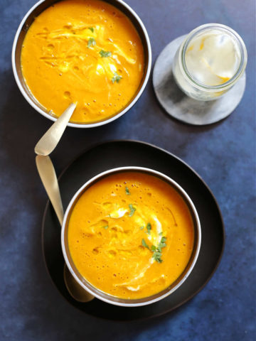 pumpkin soup recipe in a bowl with dairy-free yogurt, olive oil, and parsley stirred in