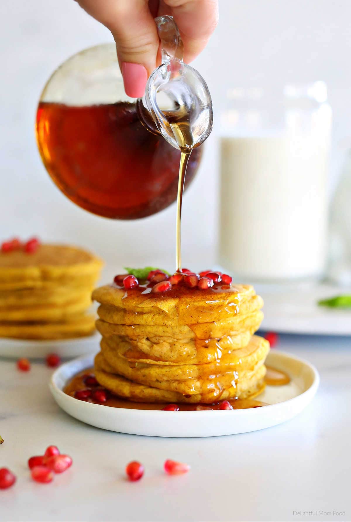 Healthy gluten free pumpkin pancake recipe with maple syrup being poured on top.