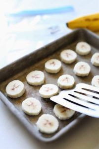 removing frozen bananas from a sheet pan with a spatula