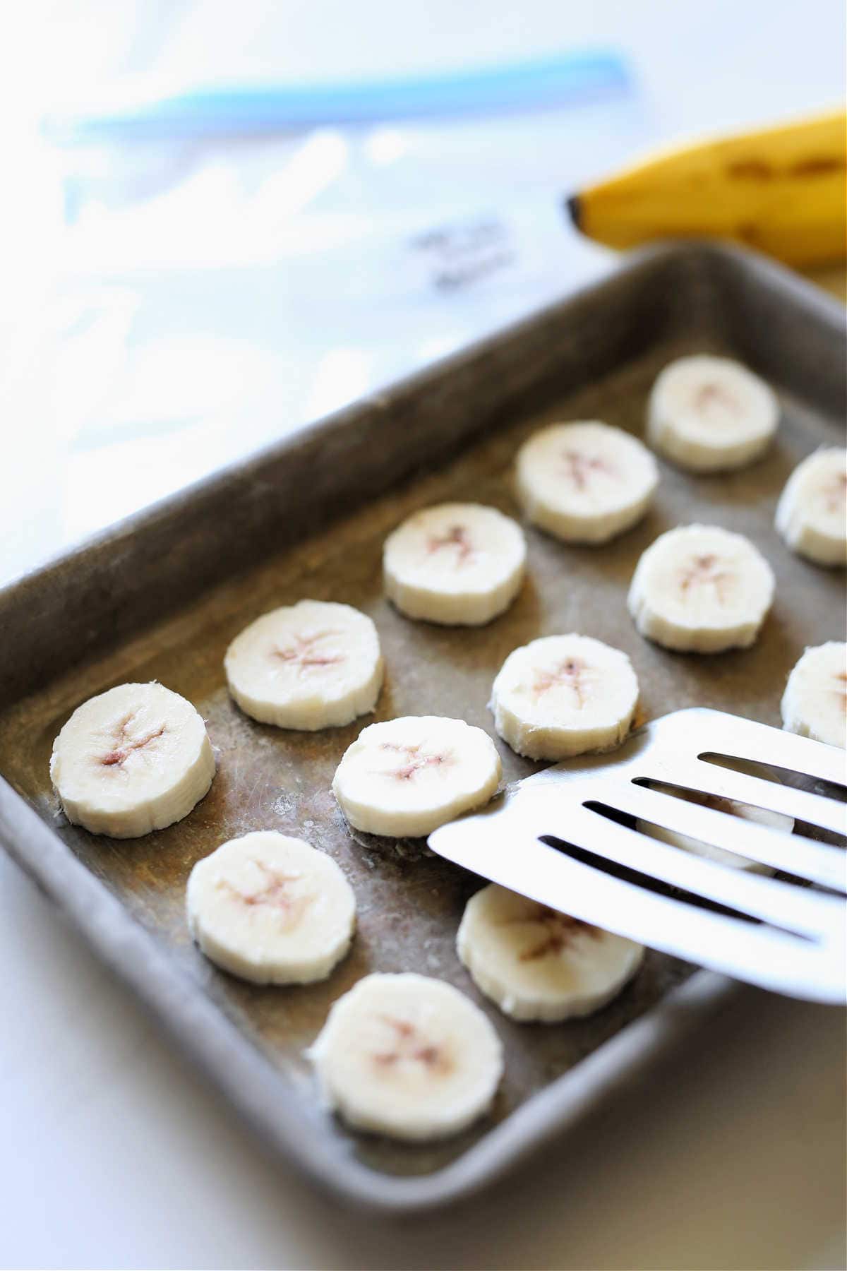 removing frozen bananas from a sheet pan with a spatula