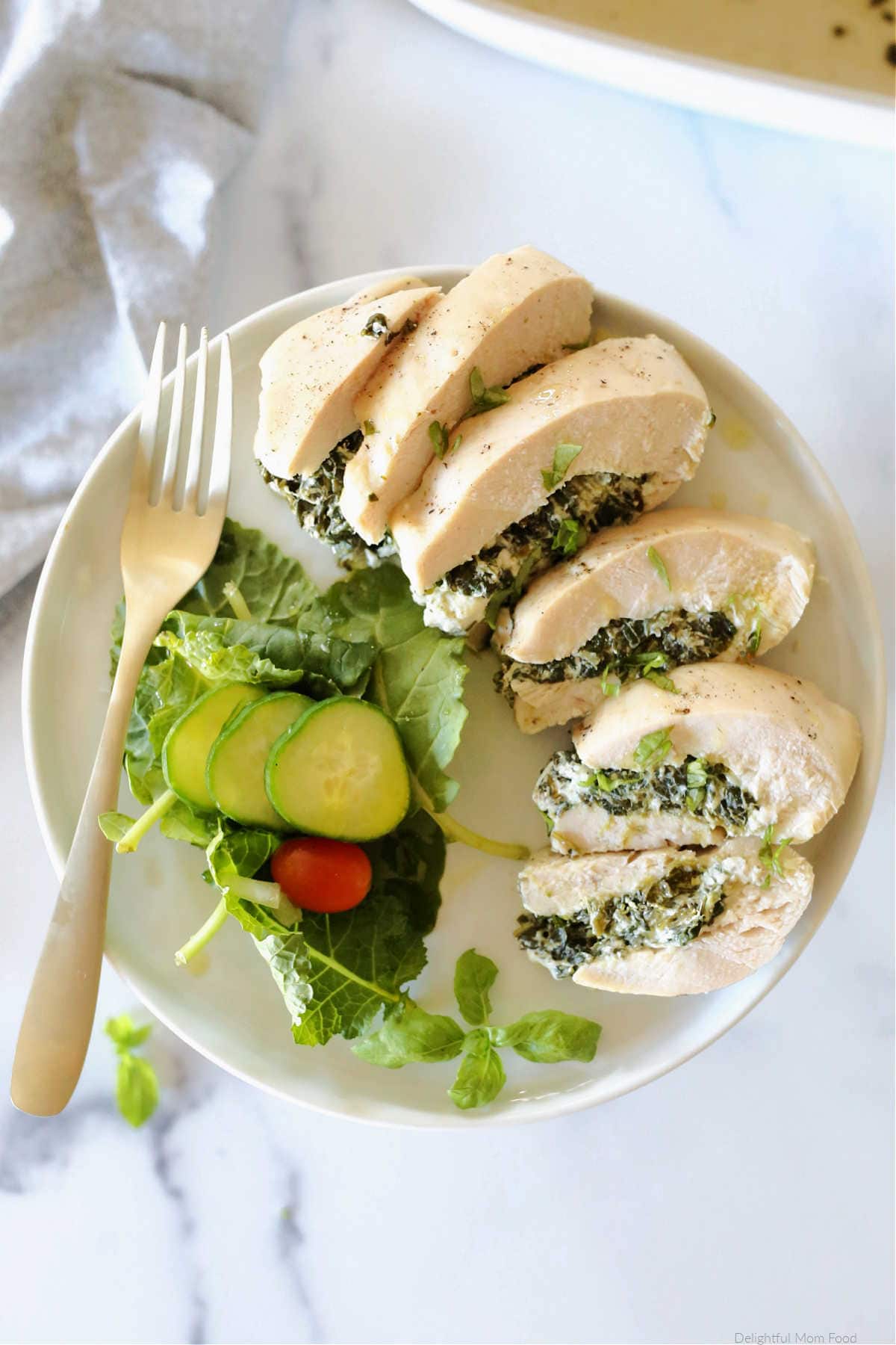 perfectly baked stuffed chicken breast sliced on a plate with a side salad
