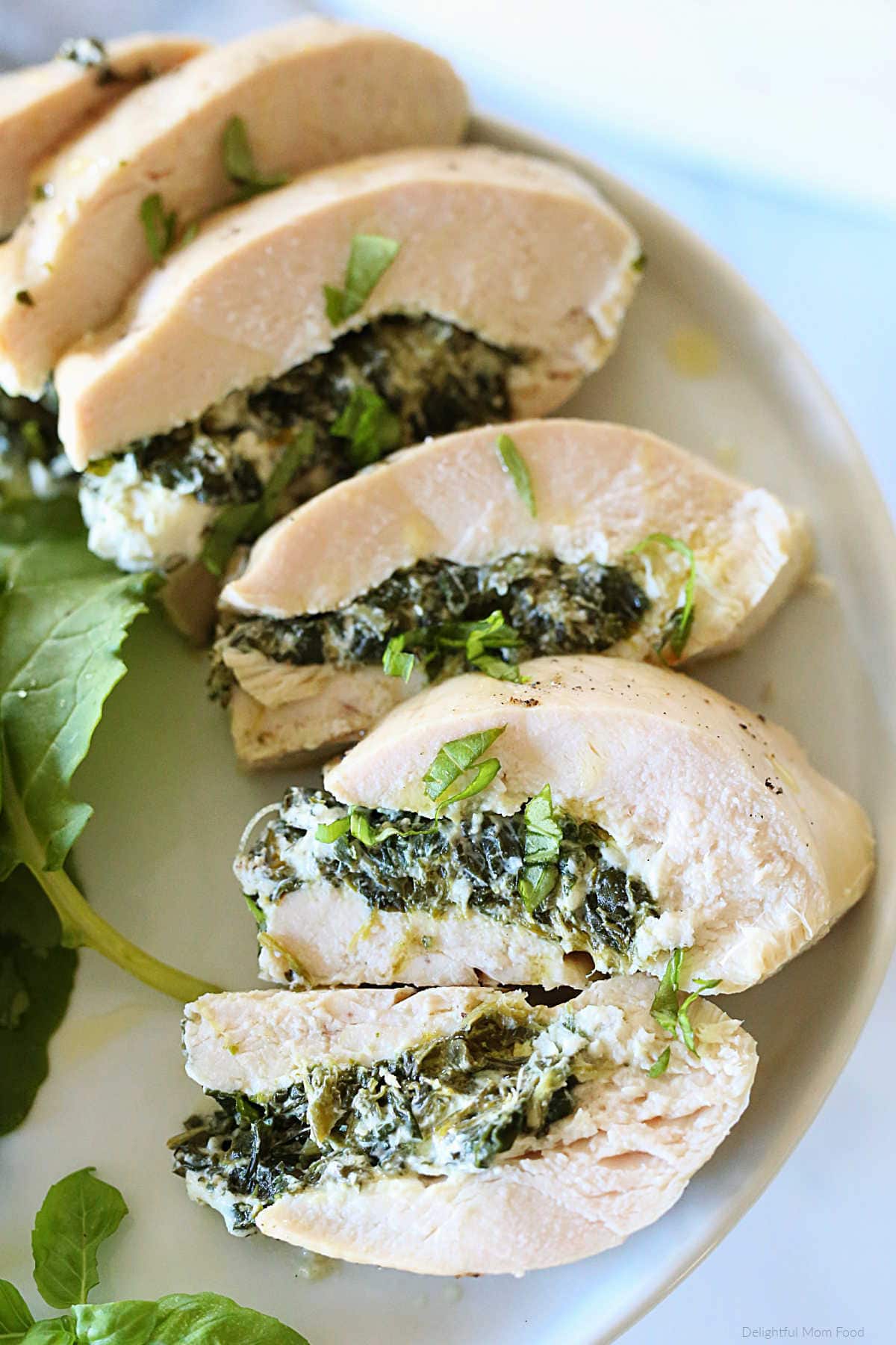 slices of goat cheese and spinach stuffed chicken recipe on a plate
