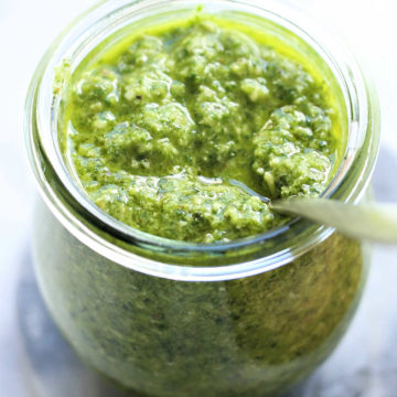 basil cilantro pesto in a glass jar with a serving spoon