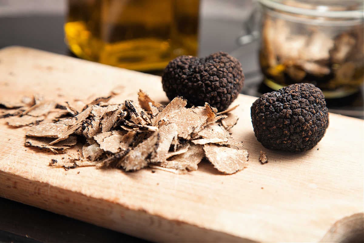 shaved pieces of black truffle on a cutting board