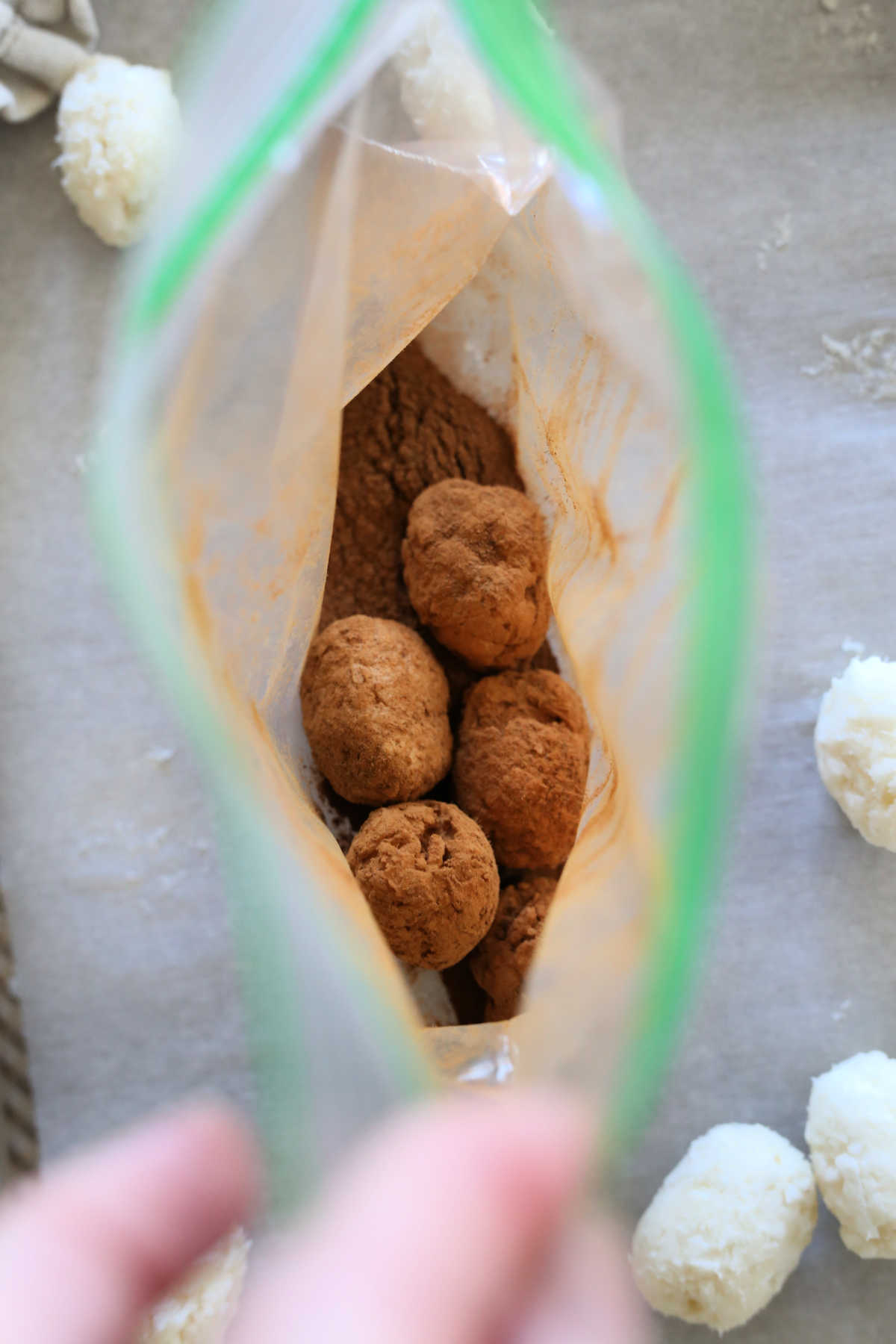 shaking coconut potato balls in a bag filled with cinnamon to make candy