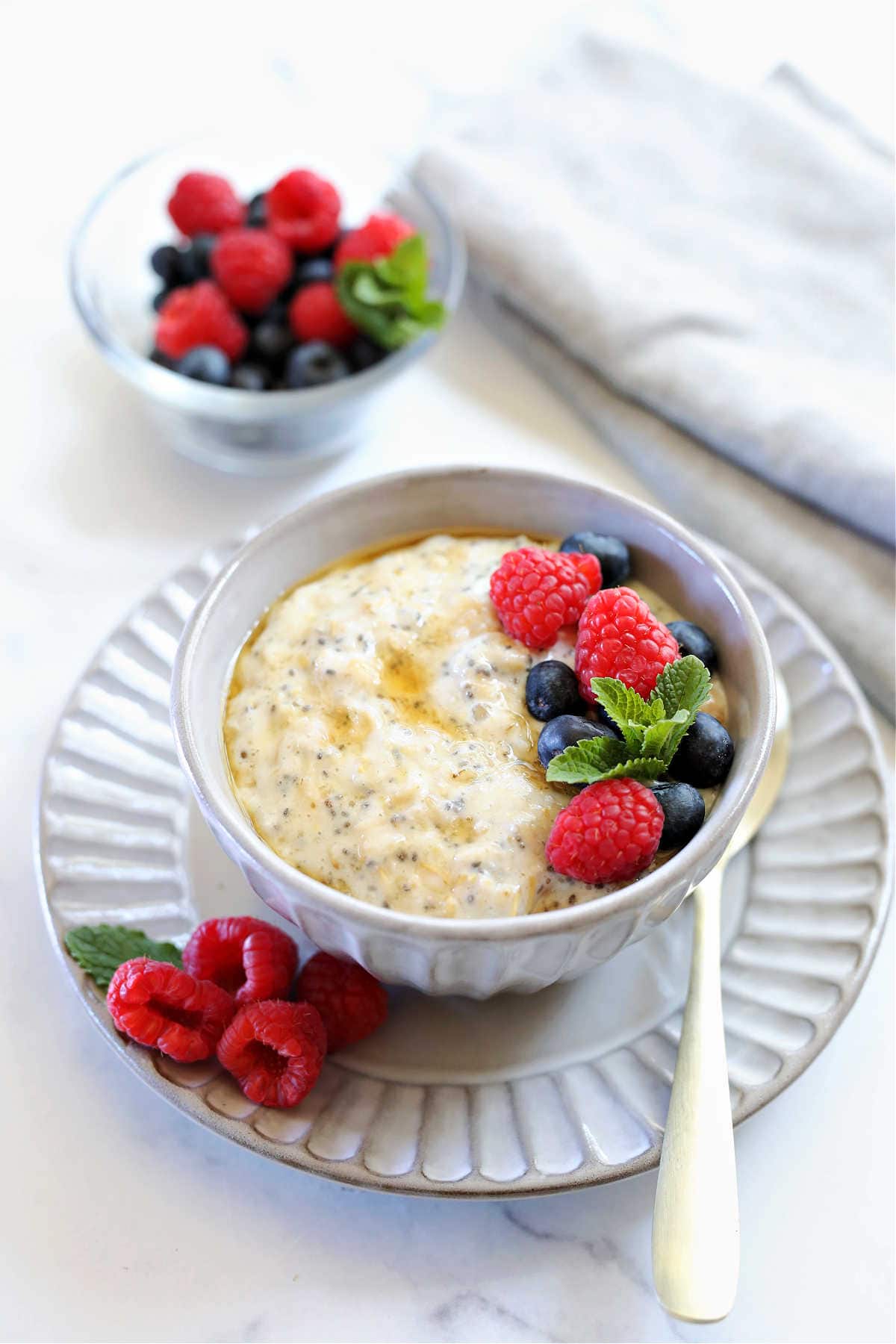 breakfast bowl of protein oatmeal in a bowl with a gold spoon and topped with berries