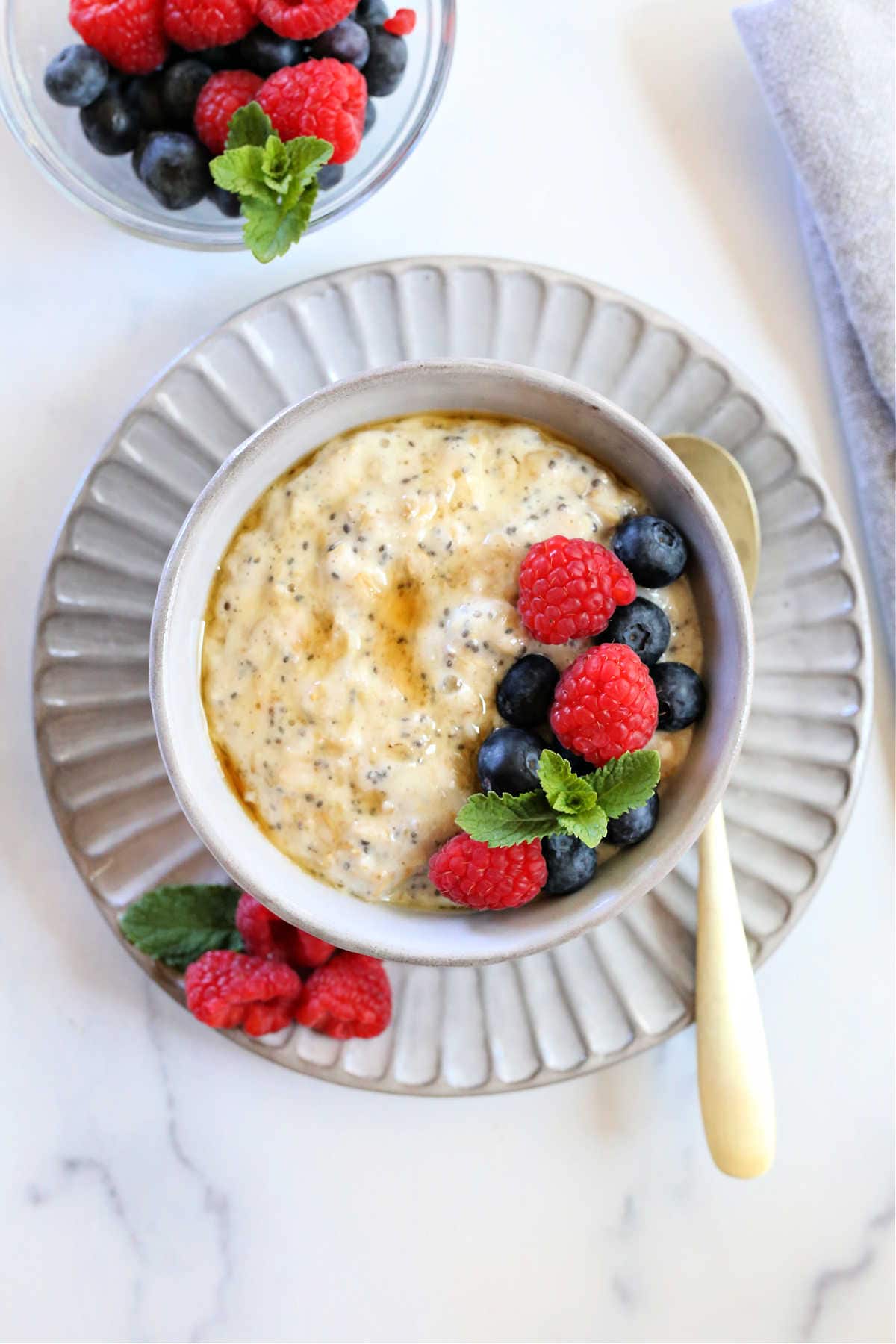 creamy chia seed protein oats in a bowl with fresh berries and a spoon