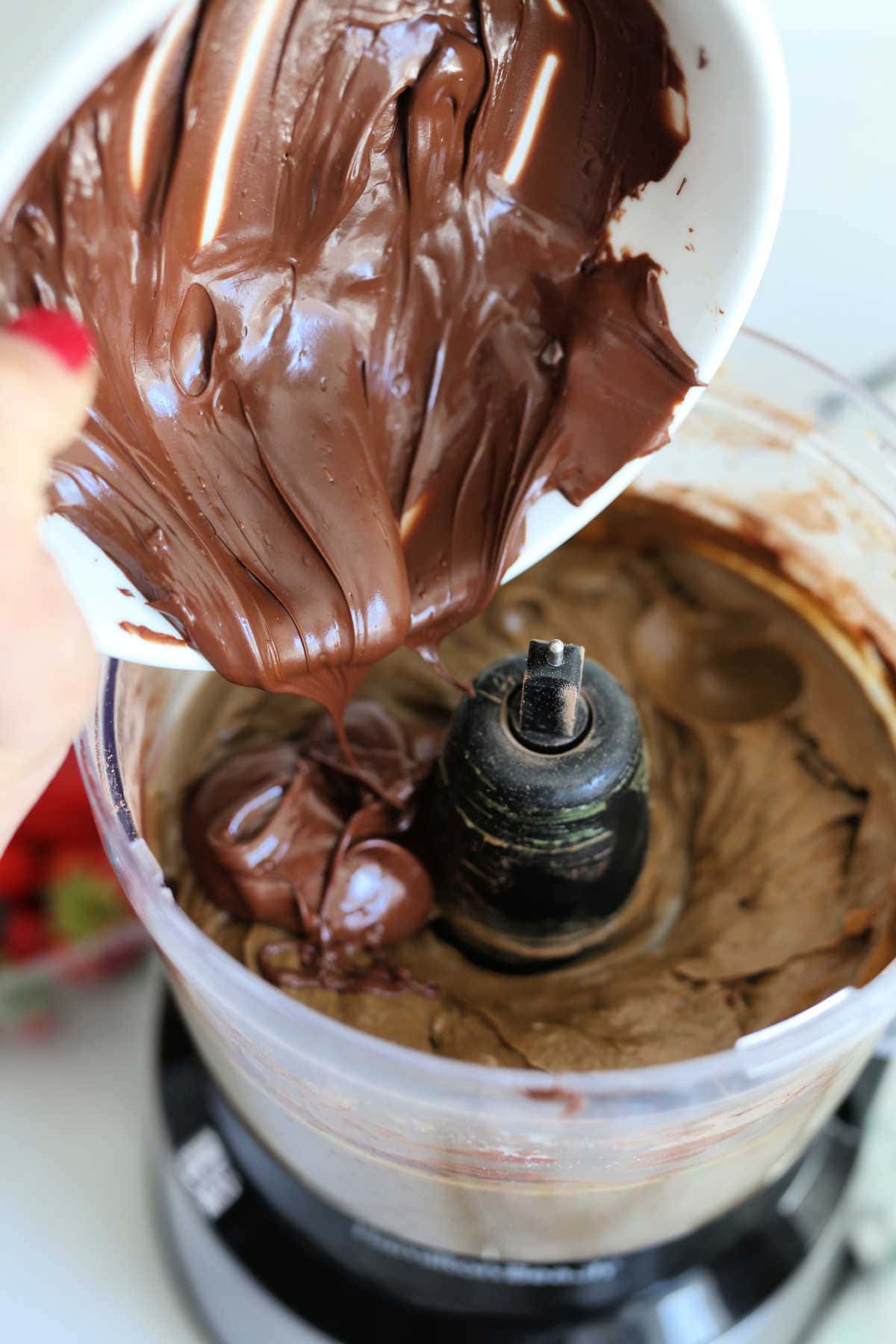 melted chocolate pouring into pudding in a food processor