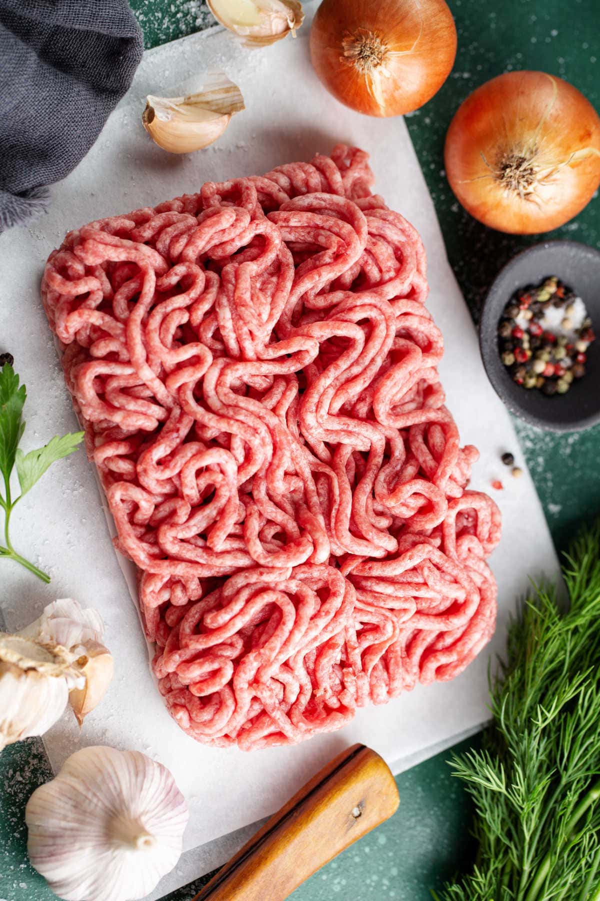 pound of ground pork or ground beef on parchment paper with vegetables