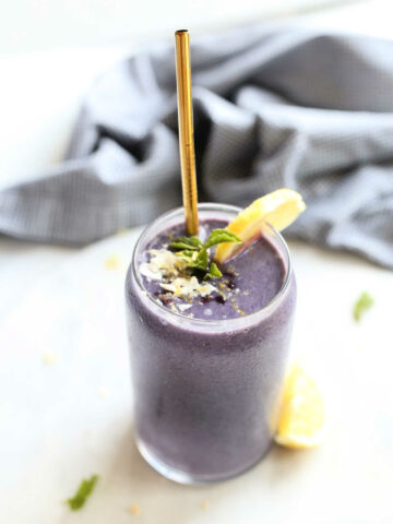 blueberry after workout smoothie in a glass with mint and a straw