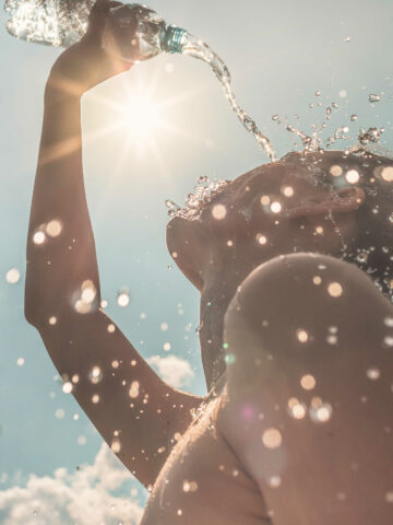 woman pouring water over face to cool off in the summer heat