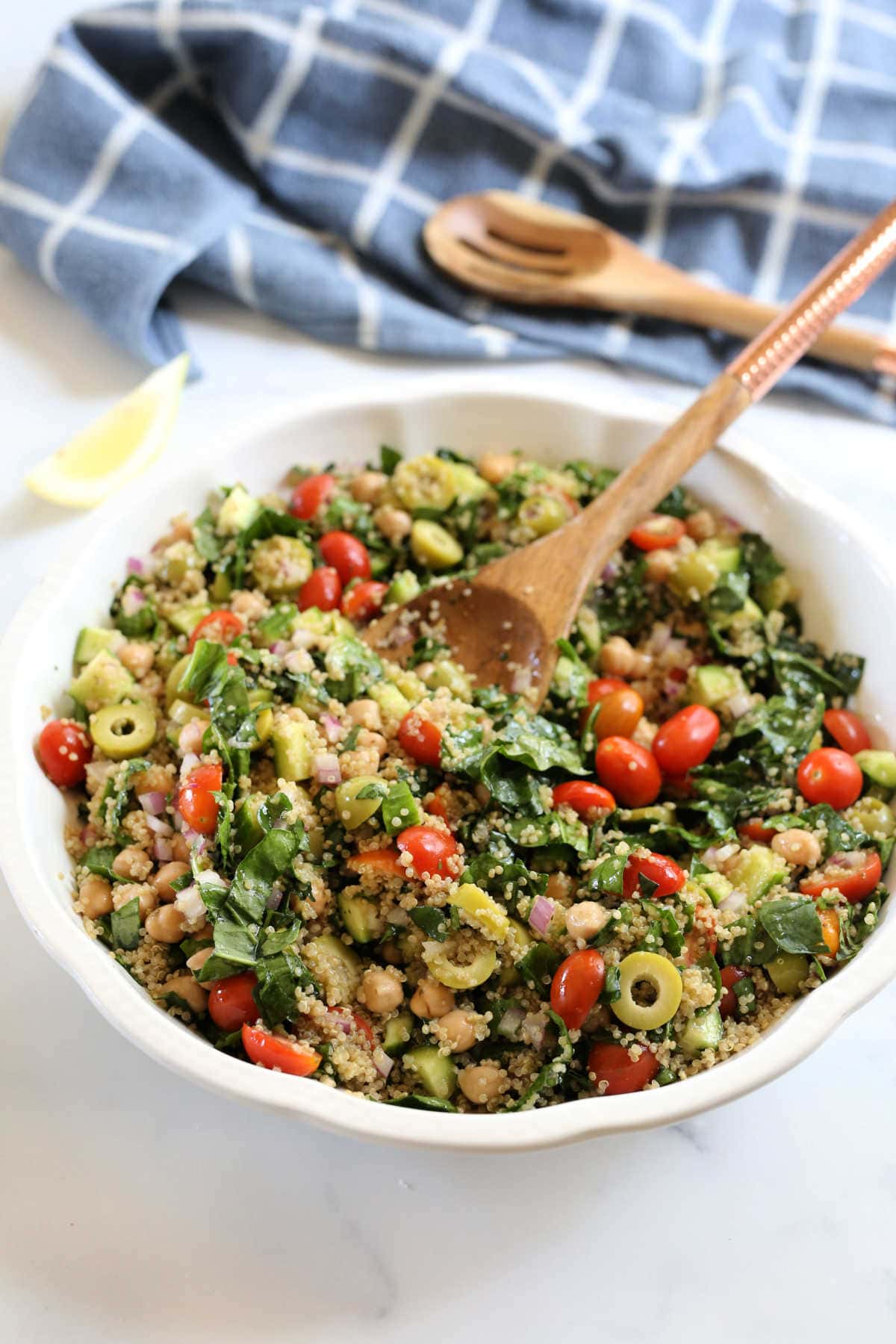 vegetable and whole grain salad in a serving platter with a wood spoon