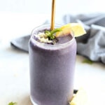 post workout smoothie made with blueberries, lemon, protein powder in a glass with a gold straw