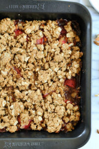 homemade crumble made with strawberries, jam, gluten-free oats layered in a baking pan