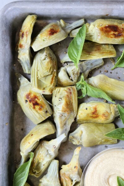 Roasted Artichokes on a baking pan with fresh basil leaves