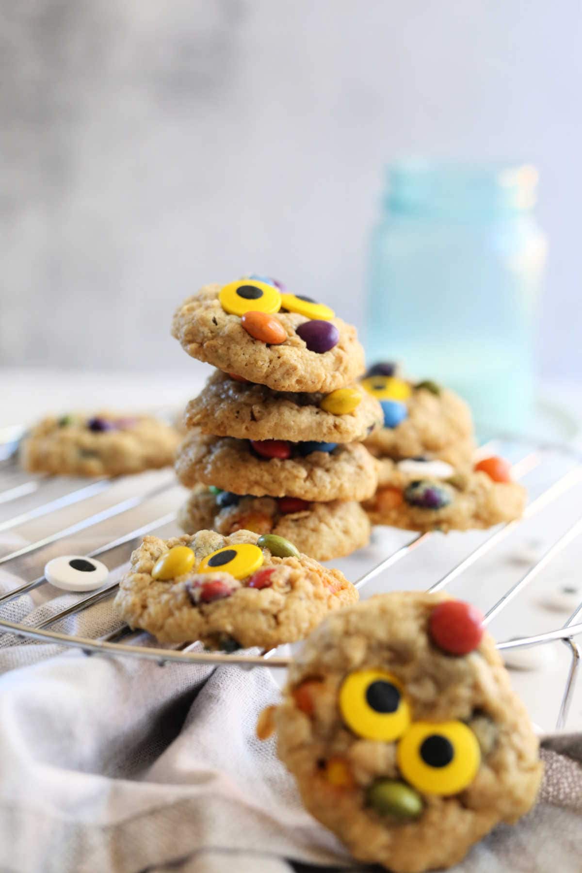 stack of gluten-free monster cookies with candy eyes on a cooling rack
