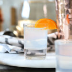 white tea shot in a shot glass garnished with mandarin wedge