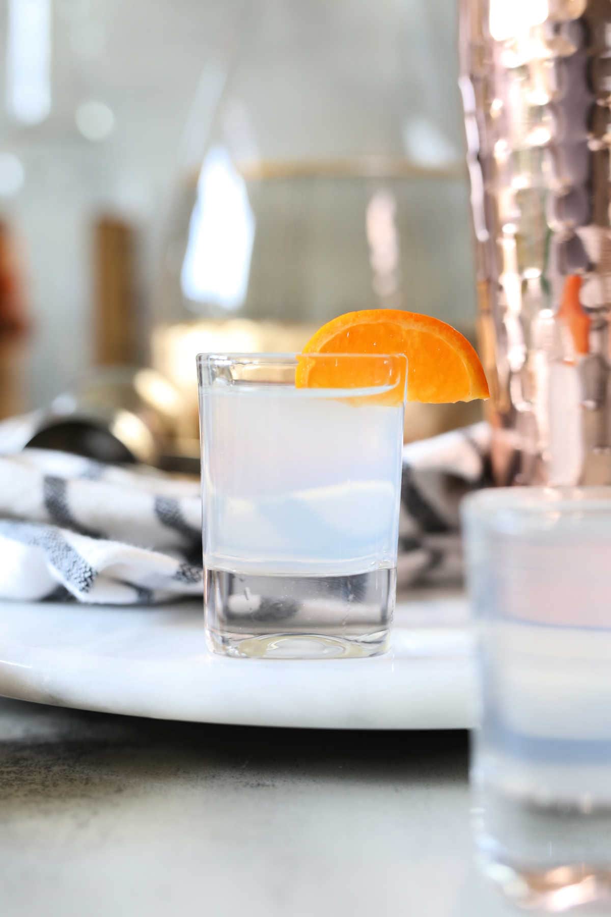 white tea shot in a shot glass garnished with mandarin wedge