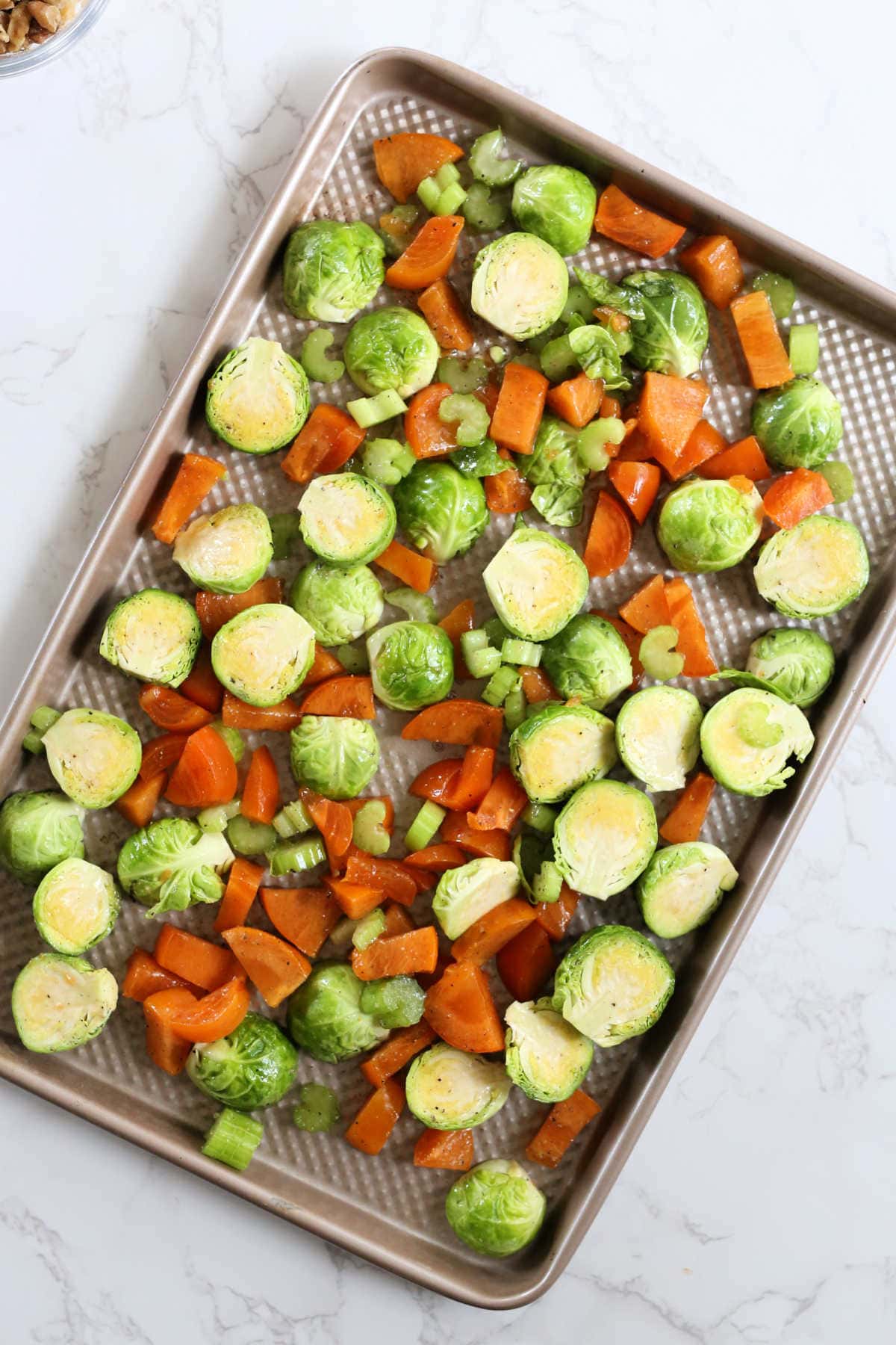 brussels sprouts persimmons and celery on a baking sheet for roasting