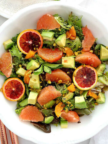 citrus salad with avocado and green lettuce in a white bowl