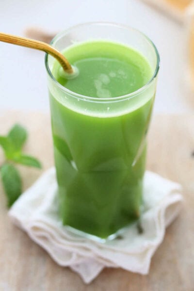 green detox juice in a glass with a gold straw