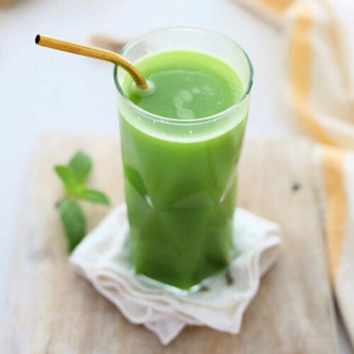 green detox juice in a glass with a gold straw