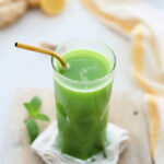 Fresh homemade green juice made with vegetables in a glass with a gold straw