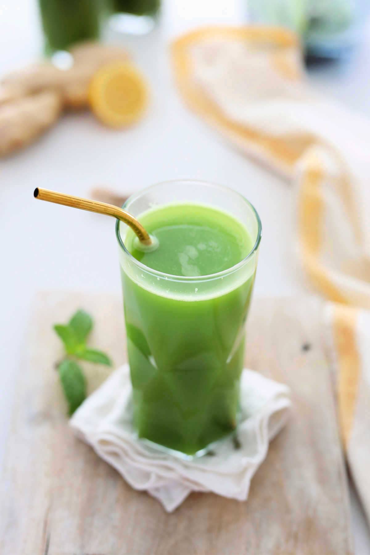 Fresh homemade green juice made with vegetables in a glass with a gold straw