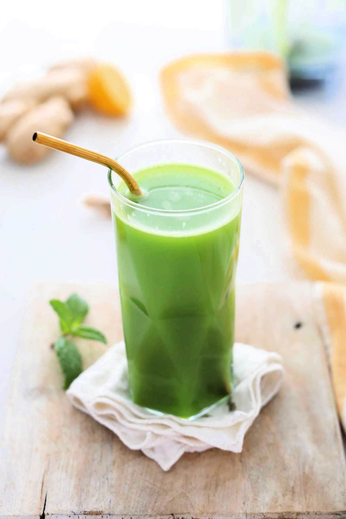 glass of green detox juice with a gold straw on a napkin