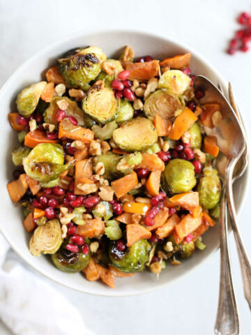 Roasted salad made with brussels sprouts in a bowl with a serving spoon and fork