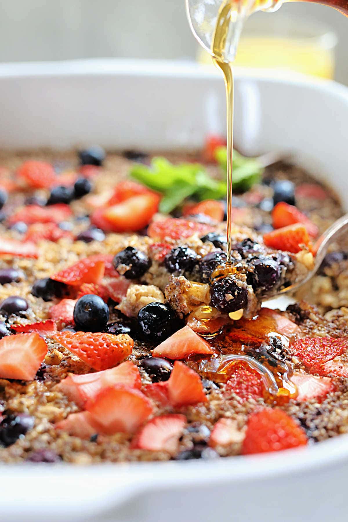 maple syrup drizzling over baked oatmeal with berries