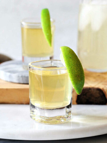 green tea shots and cocktail in glasses with fresh lime wedges