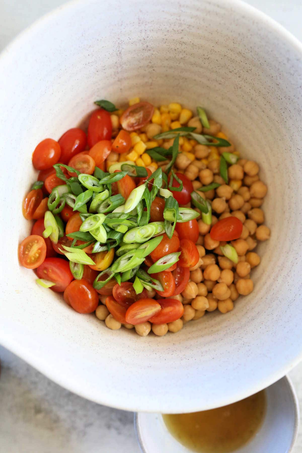 corn, chickpeas, diced green onion, grape tomatoes in a salad bowl