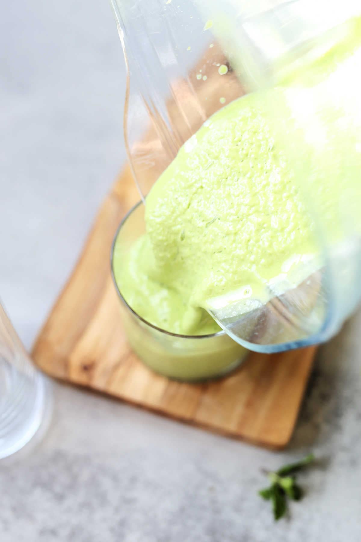 pouring a kale and banana smoothie from a blender into a glass