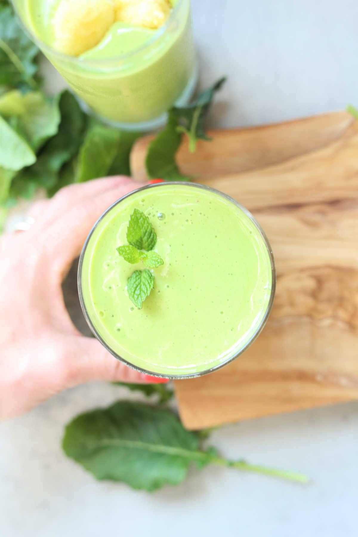 hand grabbing a glass of baby kale banana smoothie