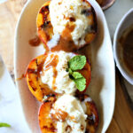 Grilled stuffed peaches and cream recipe with vanilla honey drizzled on top and fresh mint leaves.