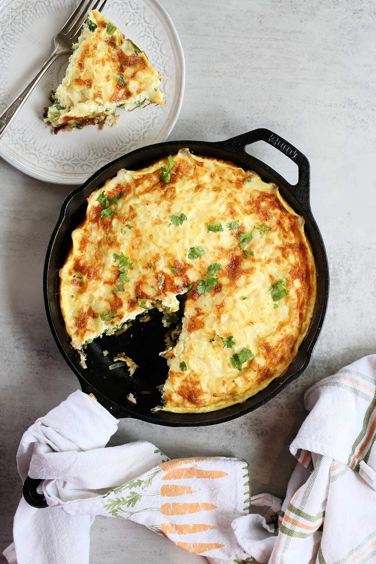 Healthy Baked Asparagus and Leek Frittata In A Cast Iron Skillet with dish towels to the side.