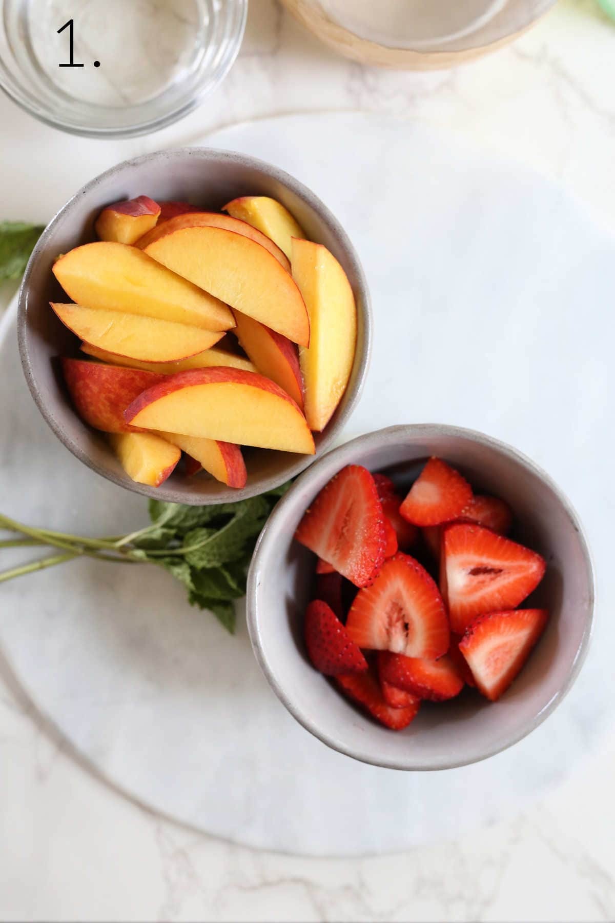 Sliced peaches and strawberries in bowls.