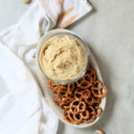 Vegan Cashew Cheese and Pretzels on a Plate with Cashew Nuts Around