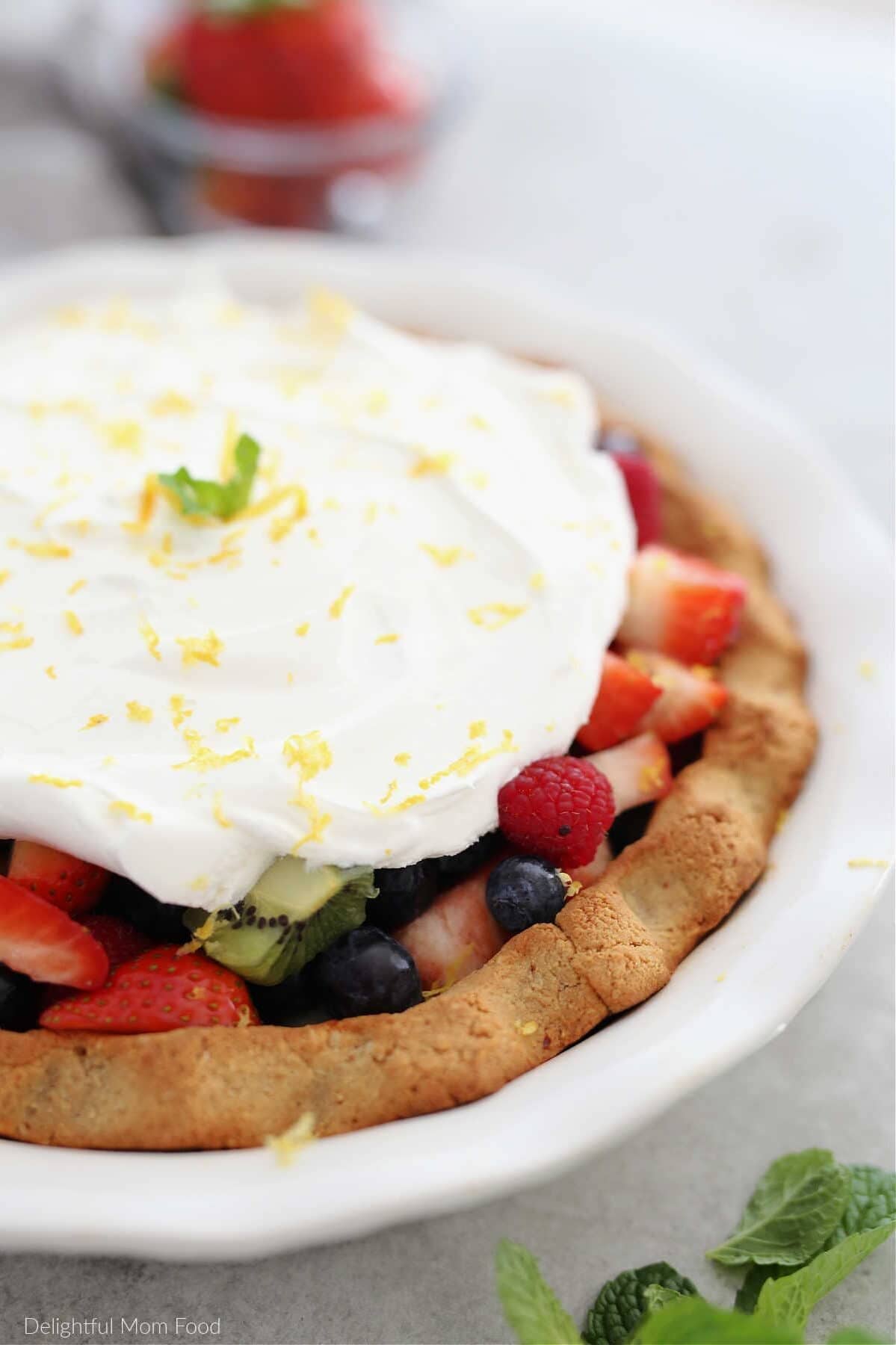 Paleo pie crust filled with fresh fruit and a whipped topping.